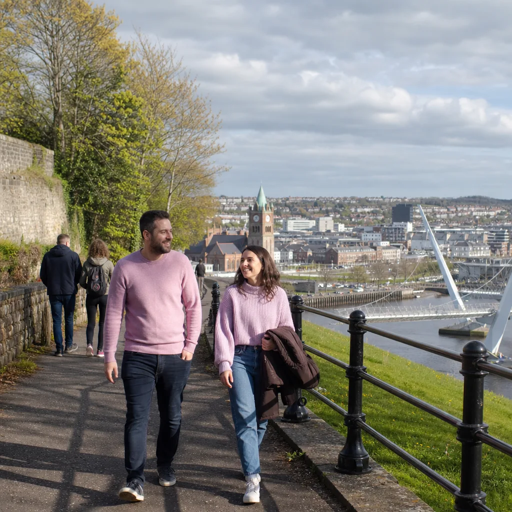 A couple walking near Derry's city walls on a bright afternoon